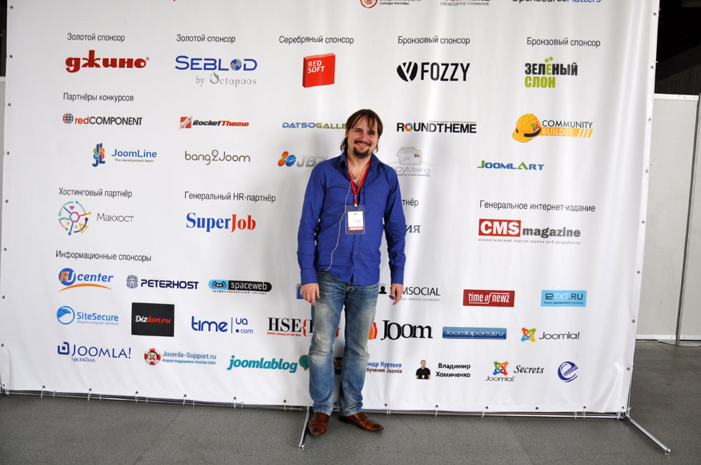 Dmitry stands on a background of JoomlaDay Russia 2014 sponsors. Here we are too :-)